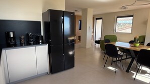 Eine moderne Küche mit einem schwarzen Kühlschrank, einer Kaffeemaschine und einem Essbereich mit Tisch und Stühlen.