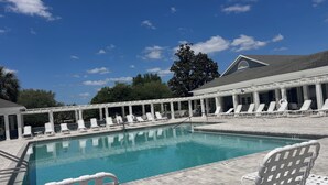 A pool area with white chairs and a covered seating area. - Beautiful 3-bedroom house on private cul-de-sac with Golf Cart in The Villages (The Villages)