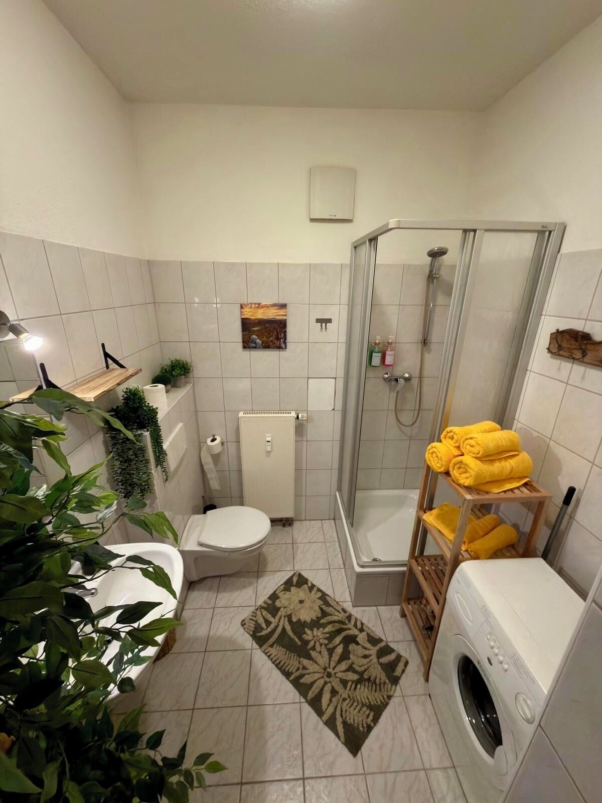 Een kleine badkamer met toilet, douche en wasmachine.