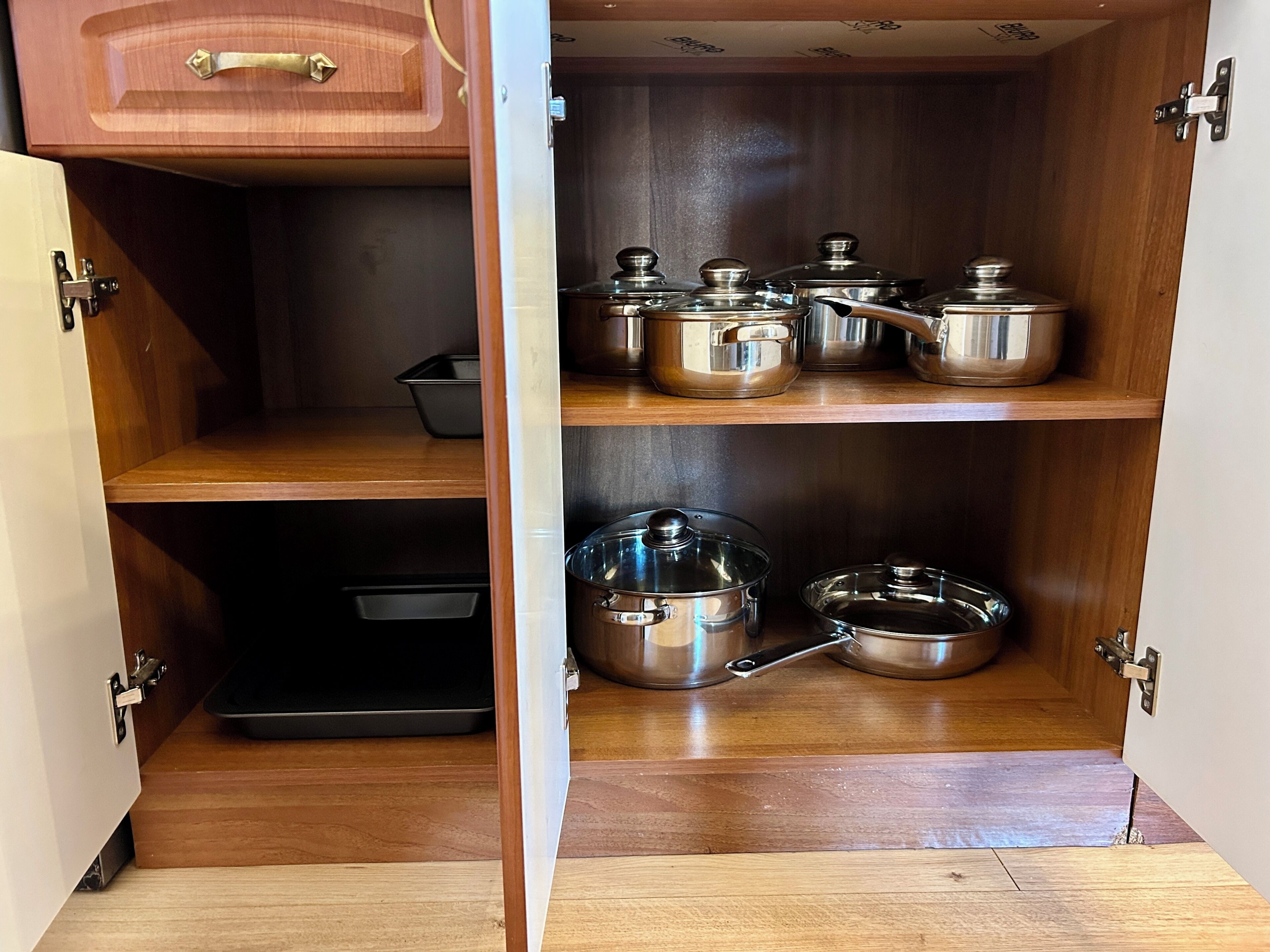A kitchen with wooden cabinets and stainless steel cookware.