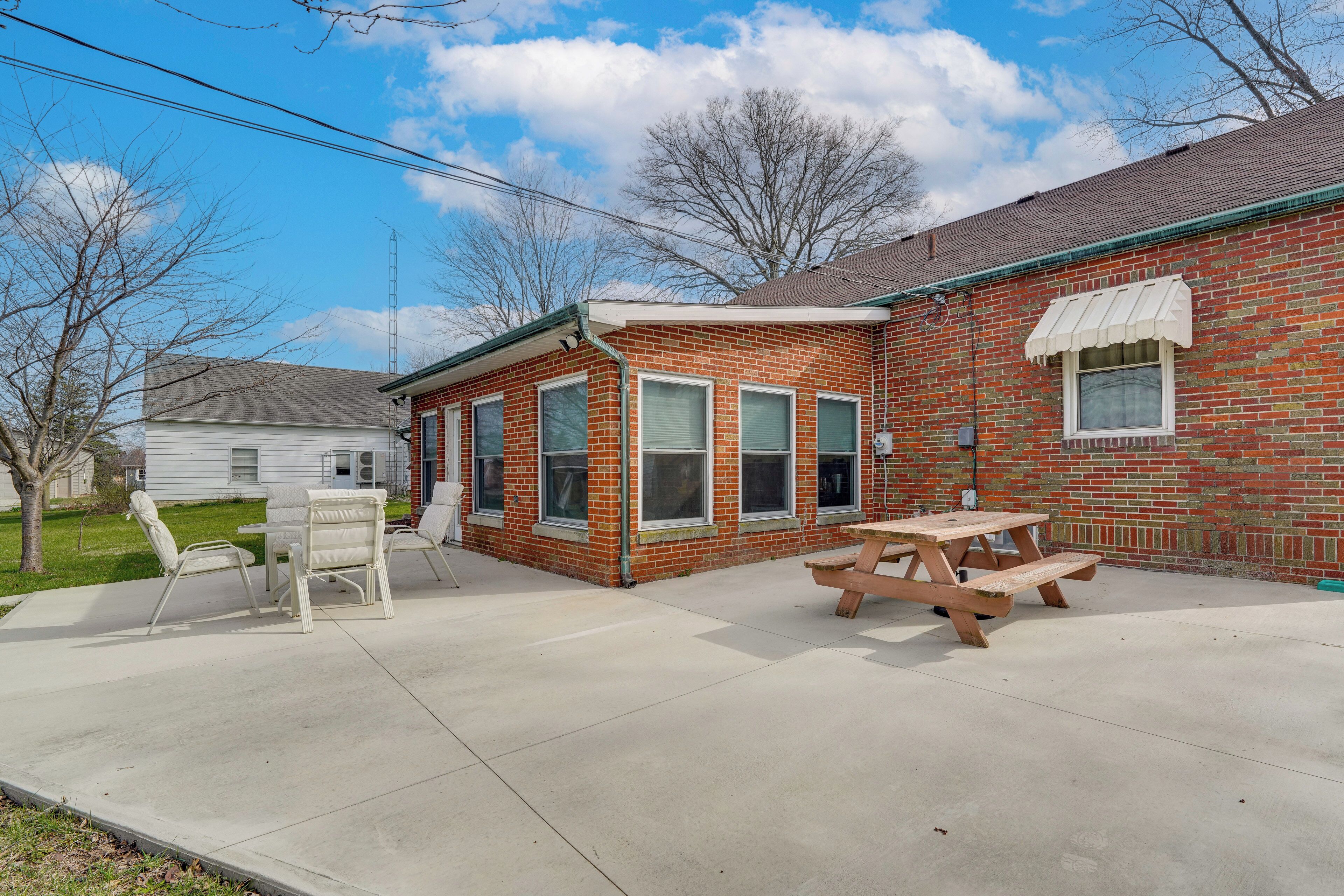 A brick house with a patio, a picnic table, and a covered seating area.