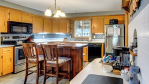 A kitchen with wooden cabinets, a microwave, a stove, a sink, a refrigerator, and a coffee maker.