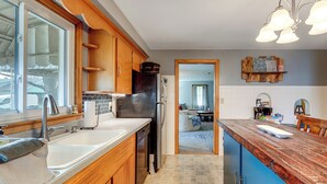 A kitchen with wooden cabinets, a stainless steel refrigerator, and a large island with a wooden countertop. - 1 Mi to Dtwn Tiffin! Brick Bungalow w/ Patio, Yard (Tiffin)