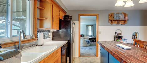 A kitchen with wooden cabinets, a stainless steel refrigerator, and a large island with a wooden countertop.