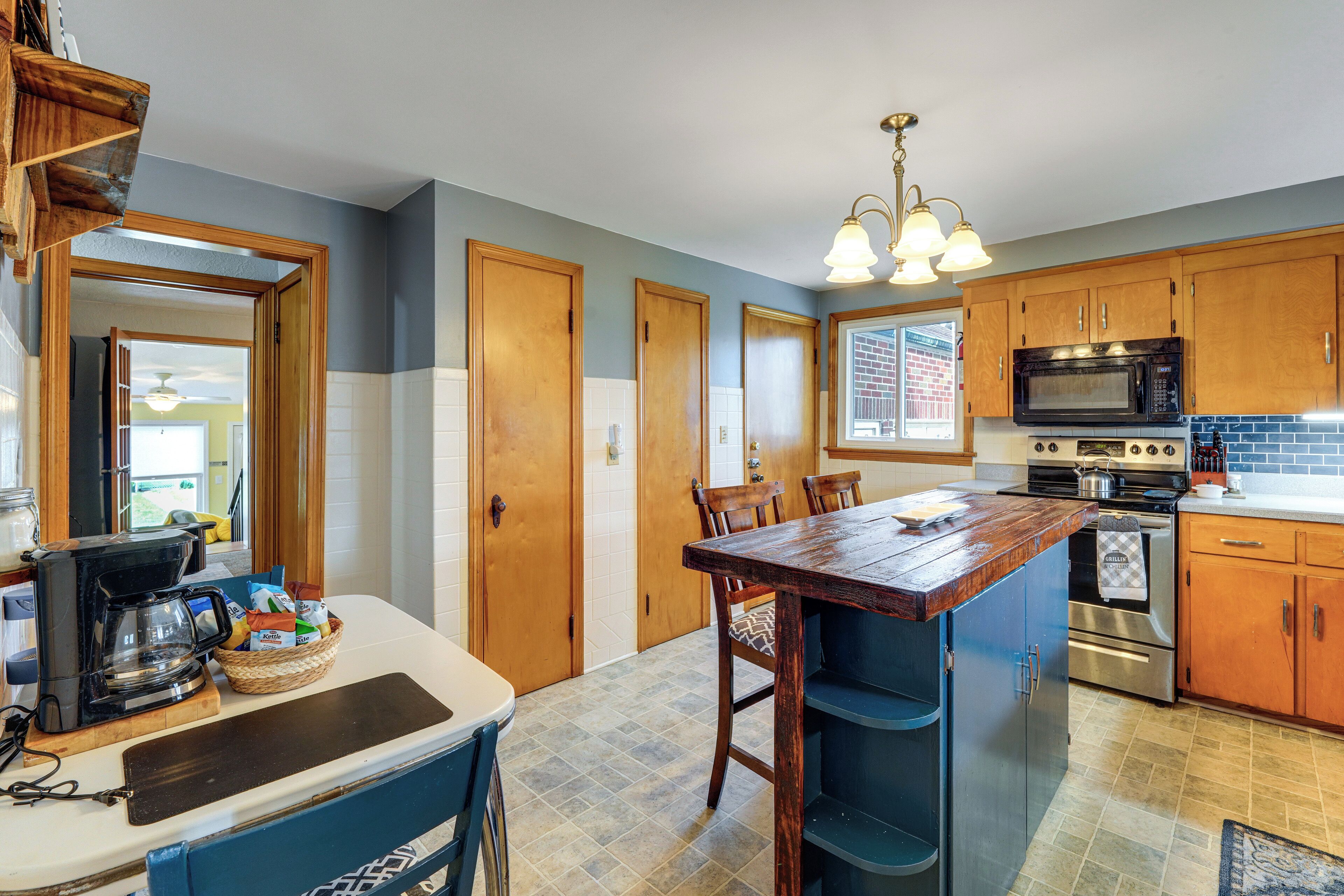 A kitchen with wooden cabinets, a coffee maker, and a large island with chairs.