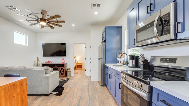 A modern kitchen with a microwave, oven, and stove. There is a dining area with a sofa and a wooden table. - Outdoor Space, Near Everything: Glendale Getaway! (Glendale)