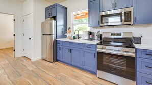 A modern kitchen with stainless steel appliances, blue cabinets, and a wooden floor. - Outdoor Space, Near Everything: Glendale Getaway! (Glendale)
