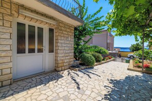 Une maison en pierre avec une porte blanche, une allée pavée et une vue sur la mer.