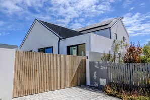 Ein modernes Haus mit Satteldach, Holzzaun und befestigter Auffahrt.