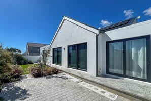 Ein modernes Gebäude mit großen Fenstern, einem gepflasterten Weg und Solaranlagen.