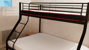 Un lit superposé avec un matelas, une structure en métal et une fenêtre au-dessus.