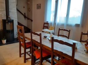 Un comedor con mesa de madera, sillas, una trona y una escalera.