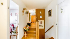 A staircase leading to a bedroom with a bed, a chair, and a vase of flowers. - Guest Room 'Chambre T' with Shared Terrace & Garden, Wi-Fi Included (Saint-Rémy-lès-Chevreuse)