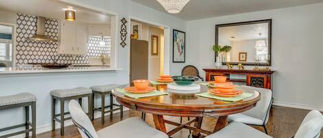 A dining area with a round table, four chairs, and a chandelier.