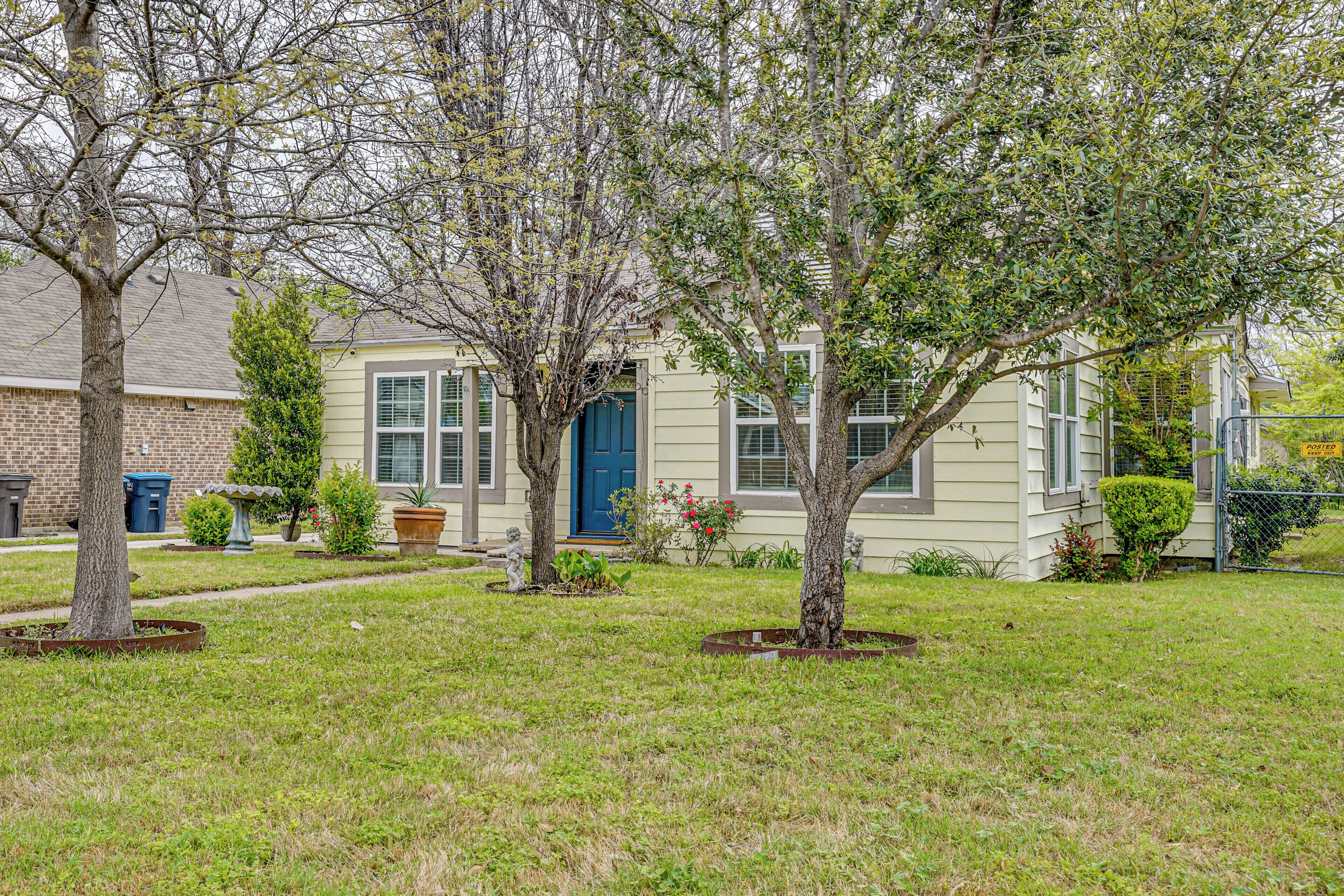A residential house with a front yard, a blue door, and a brick wall.