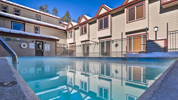 A swimming pool with a clear reflection, a no parking sign, and a building with multiple windows and a door. - Steps From Ski Shuttle! WP Condo w/ Heated Pool (Winter Park)