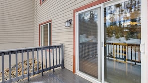 A covered deck with a railing, a sliding glass door, and a stone ledge. - Condo 3 Mi to Winter Park Resort: Community Perks! (Winter Park)