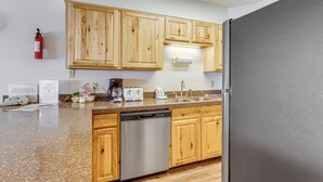 A kitchen with wooden cabinets, a stainless steel dishwasher, a refrigerator, a coffee maker, and a sink. - Walk to Hideaway Park! All-season Winter Park Gem (Winter Park)