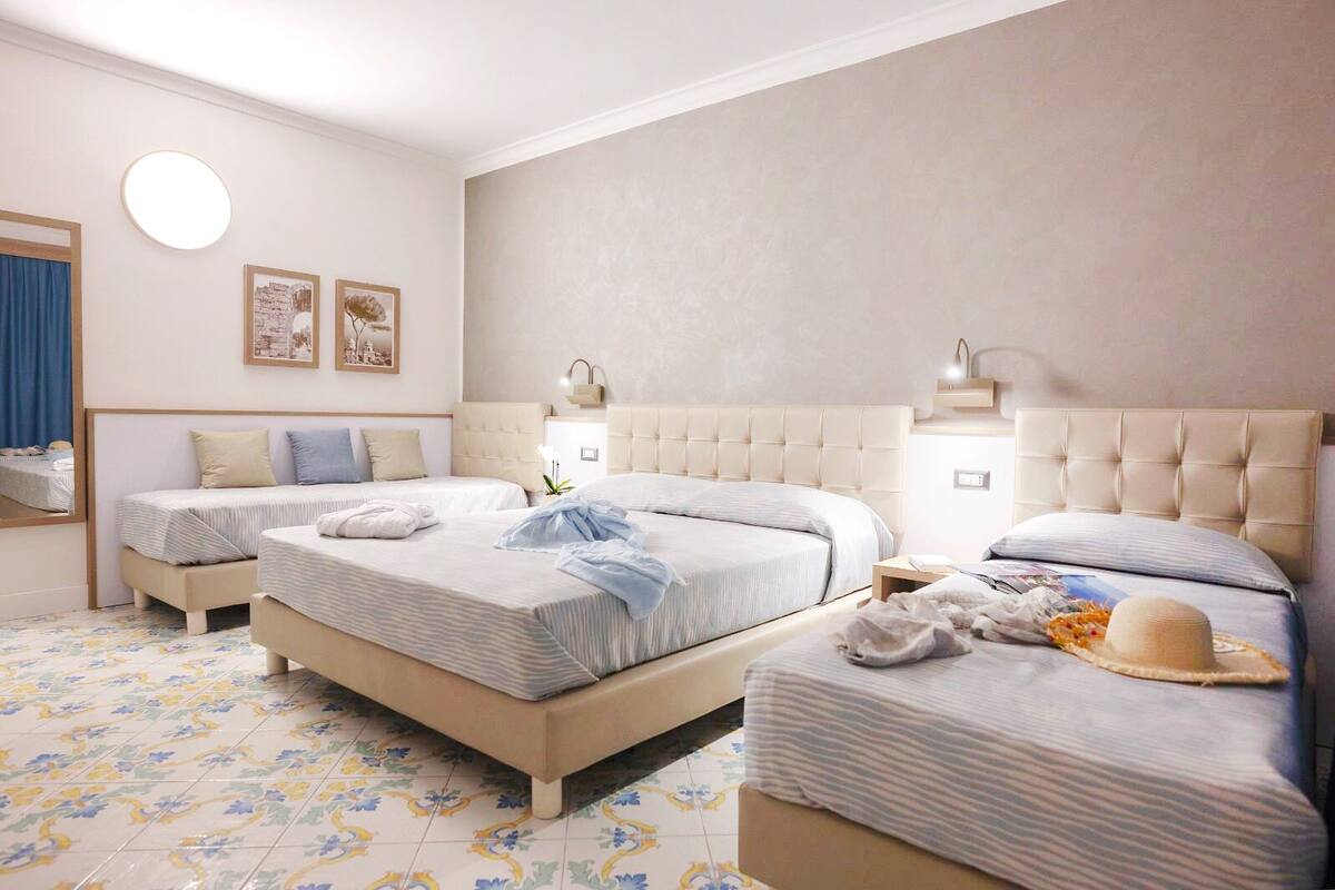 Een hotelkamer met twee bedden, een grote spiegel, een ronde lamp en een vloer met een bloemenmotief.