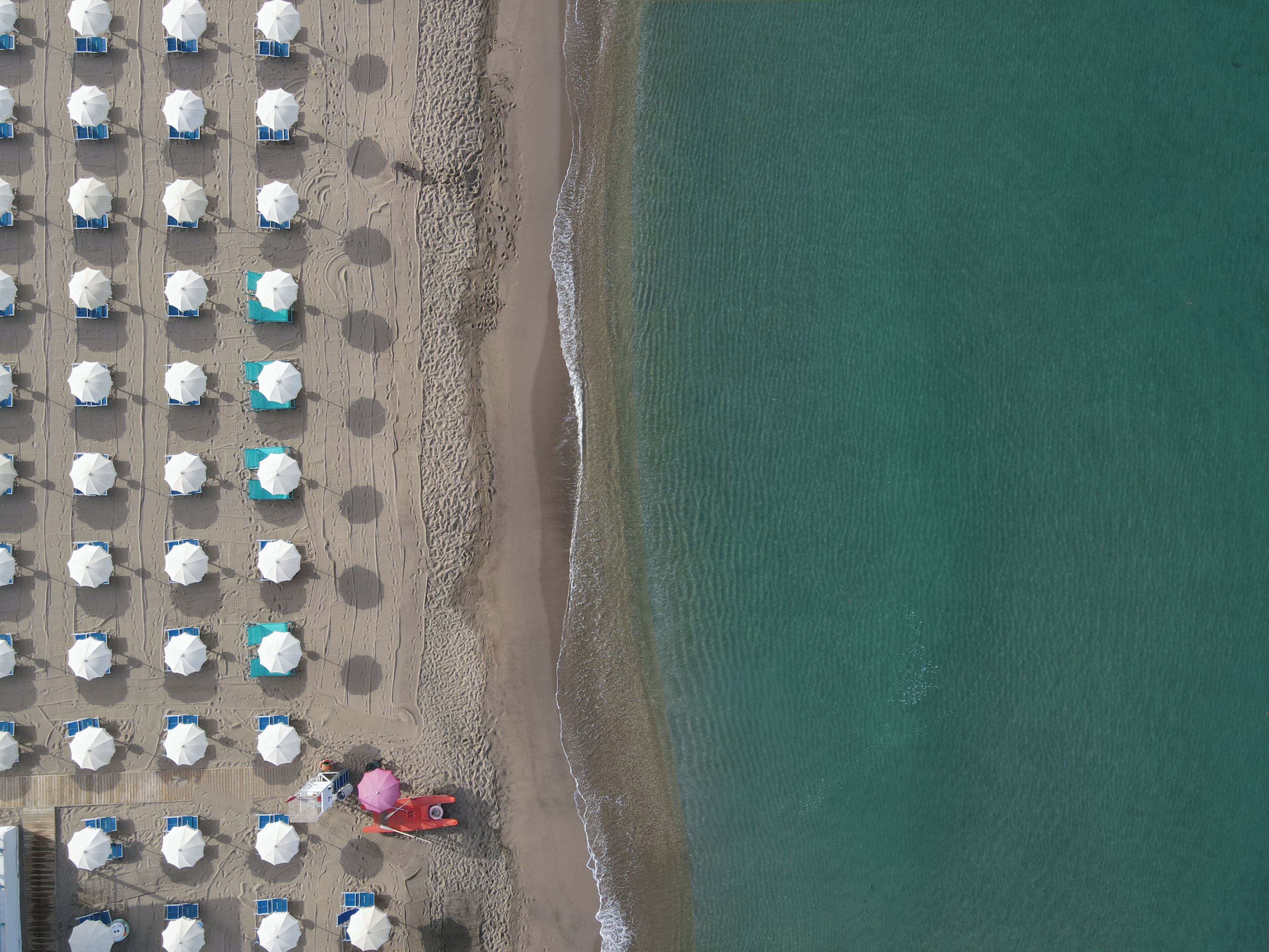 An aerial view of a beach with rows of umbrellas and sun loungers.