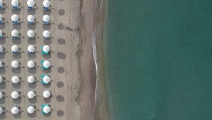 Luchtbeeld van een strand met rijen parasols en ligbedden.