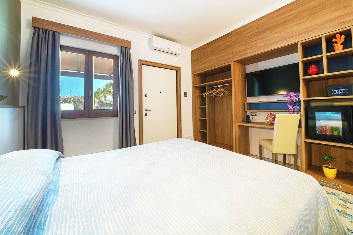 Een slaapkamer met een bed, bureau, stoel, televisie en een kledingkast.
