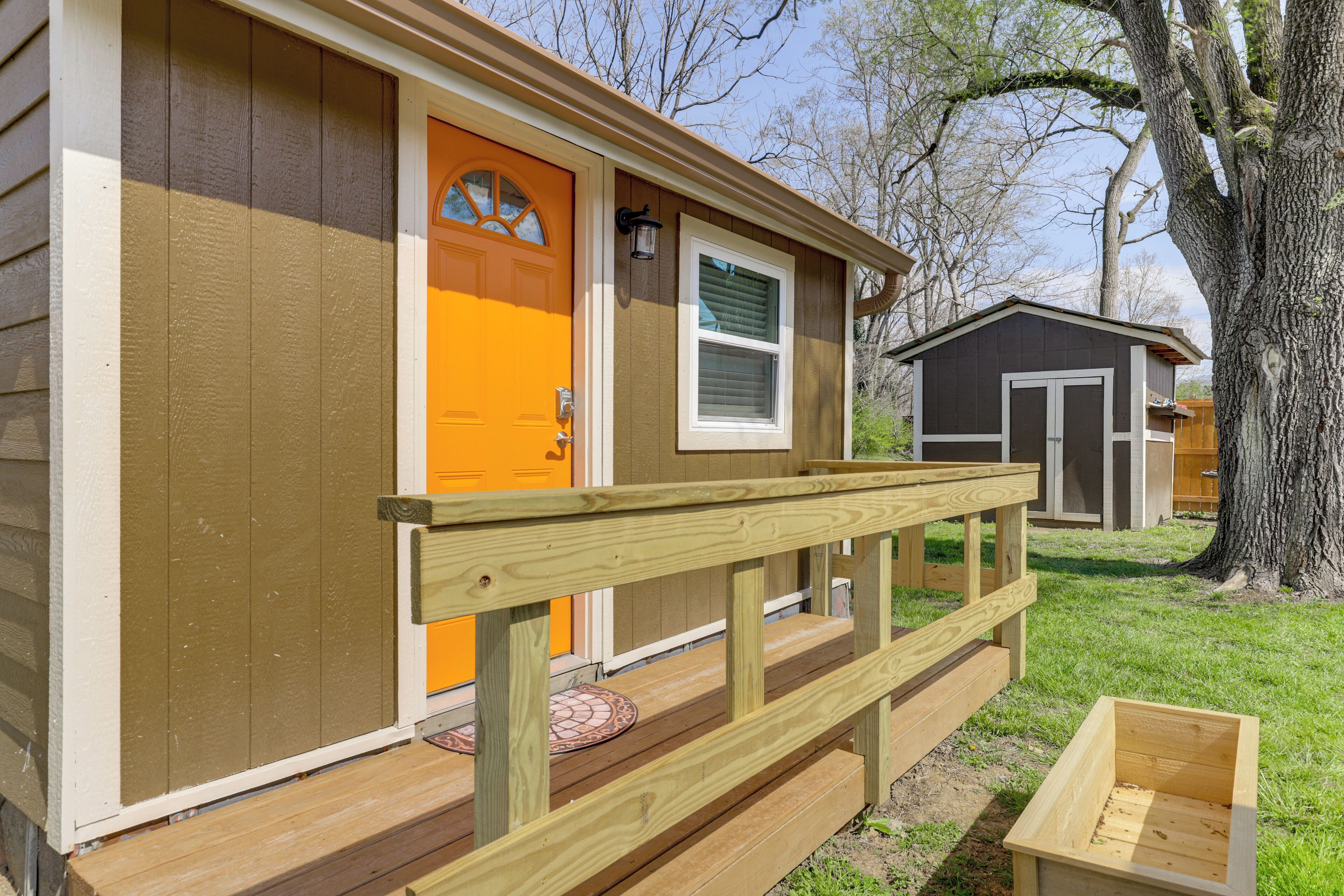 A small wooden house with a front porch, a door, and a window.