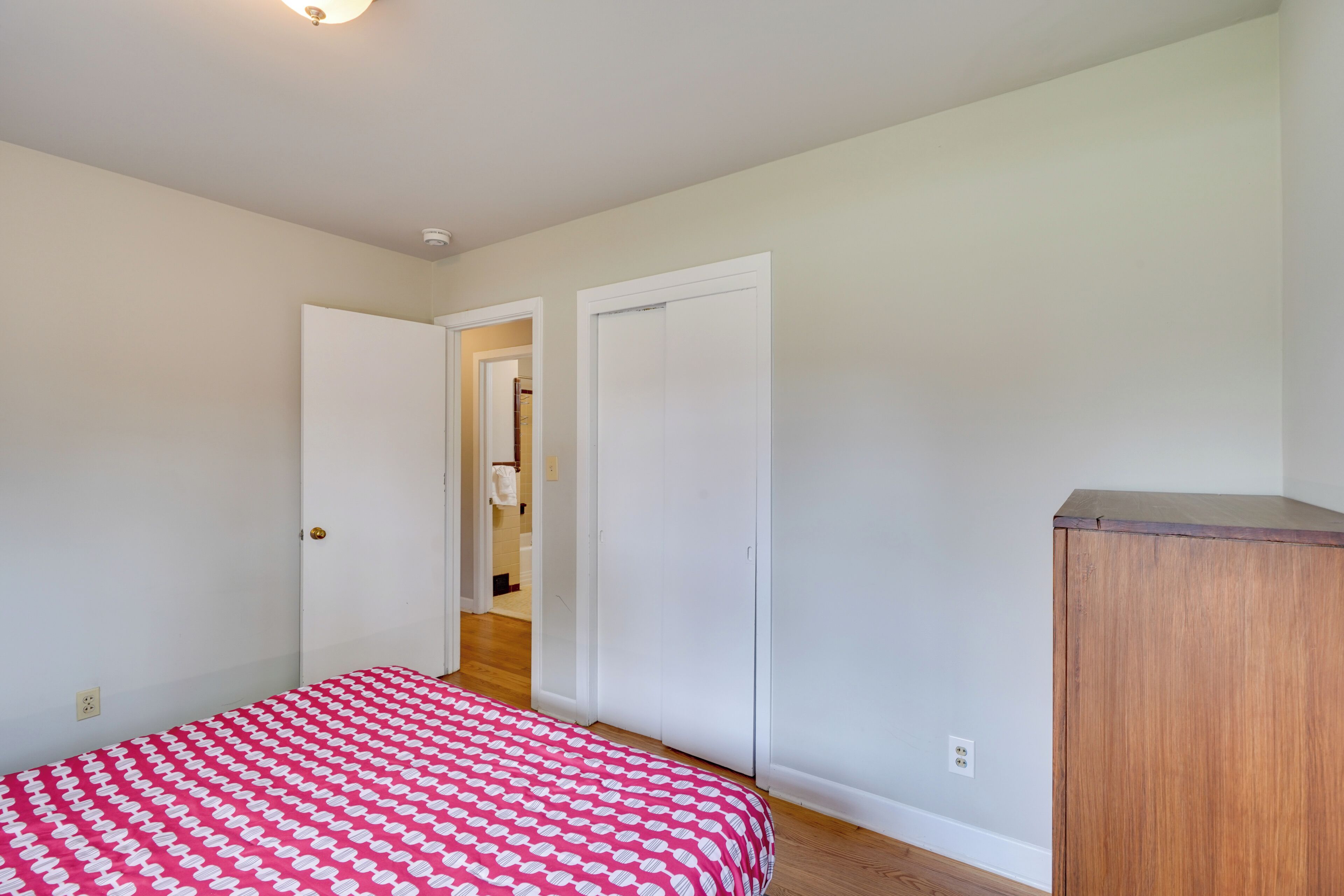 A bedroom with a bed, a wardrobe, and a door leading to another room.