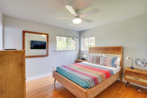 Ein Schlafzimmer mit einem Holzbett, einem Deckenventilator, einem Nachttisch und einem Spiegel.