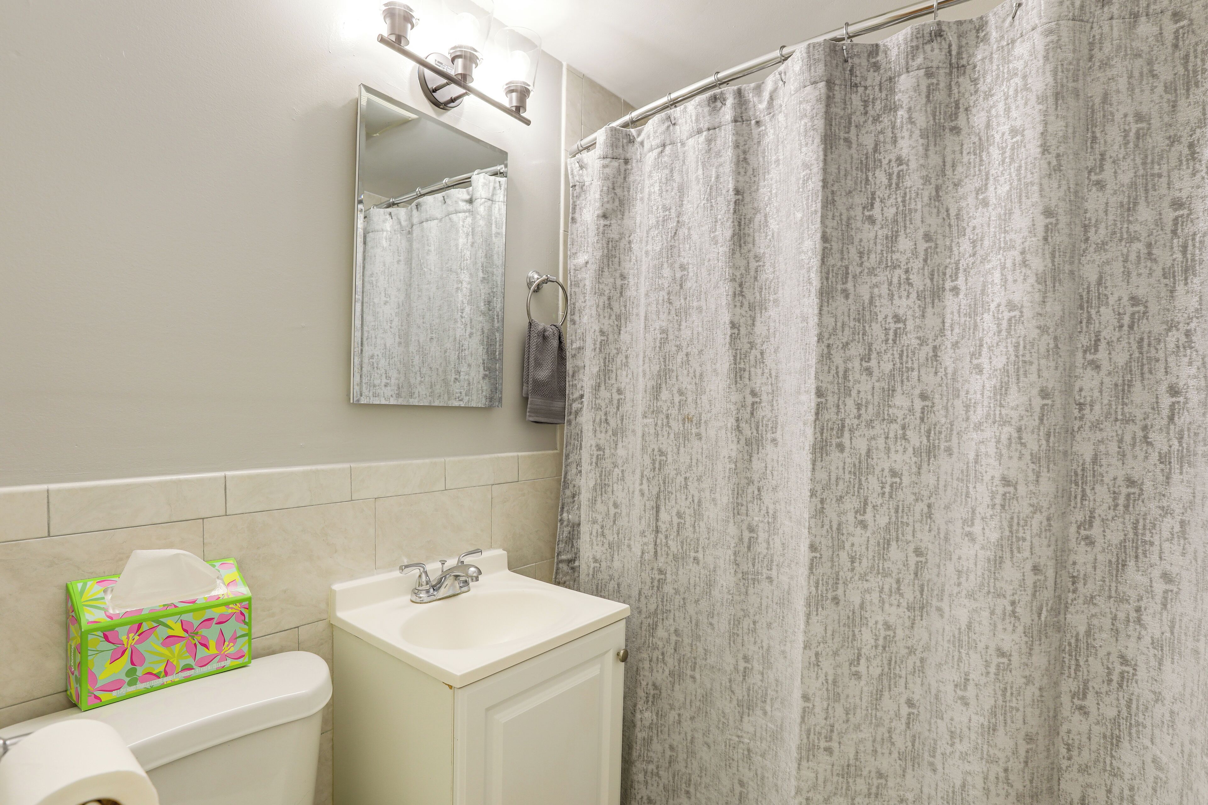 A bathroom with a toilet, sink, mirror, and shower curtain.
