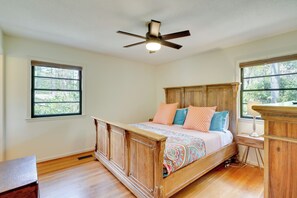 A bedroom with a wooden bed, a ceiling fan, a nightstand, and a window with a view of trees. - Quiet Downtown Cary Home w/ Screened Porch (Cary)