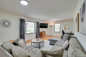 A modern living room with a grey sofa, a round coffee table, and a flat-screen TV mounted on the wall. - Quiet Downtown Cary Home w/ Screened Porch (Cary)