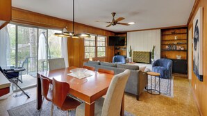 Amplia sala de estar con mesa de comedor, sofá y sillones, ventilador de techo y televisor.