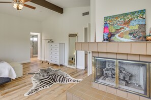 A bedroom with a fireplace, a zebra rug, a dresser, and a painting.