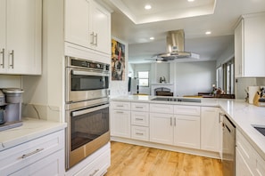 A modern kitchen with white cabinetry, stainless steel appliances, and a central island.