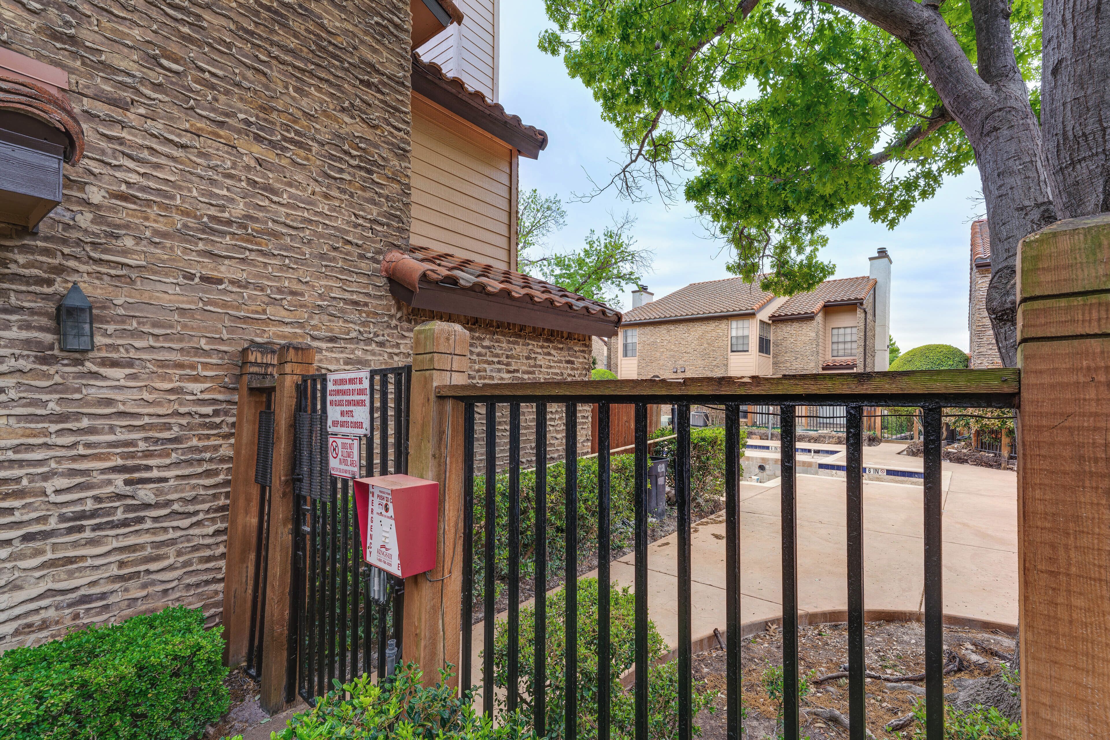 A stone building with a gated entrance, a red mailbox, and a clear view of the street.