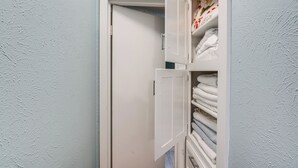 Une porte blanche, et un placard entrouvert contenant des serviettes pliées.