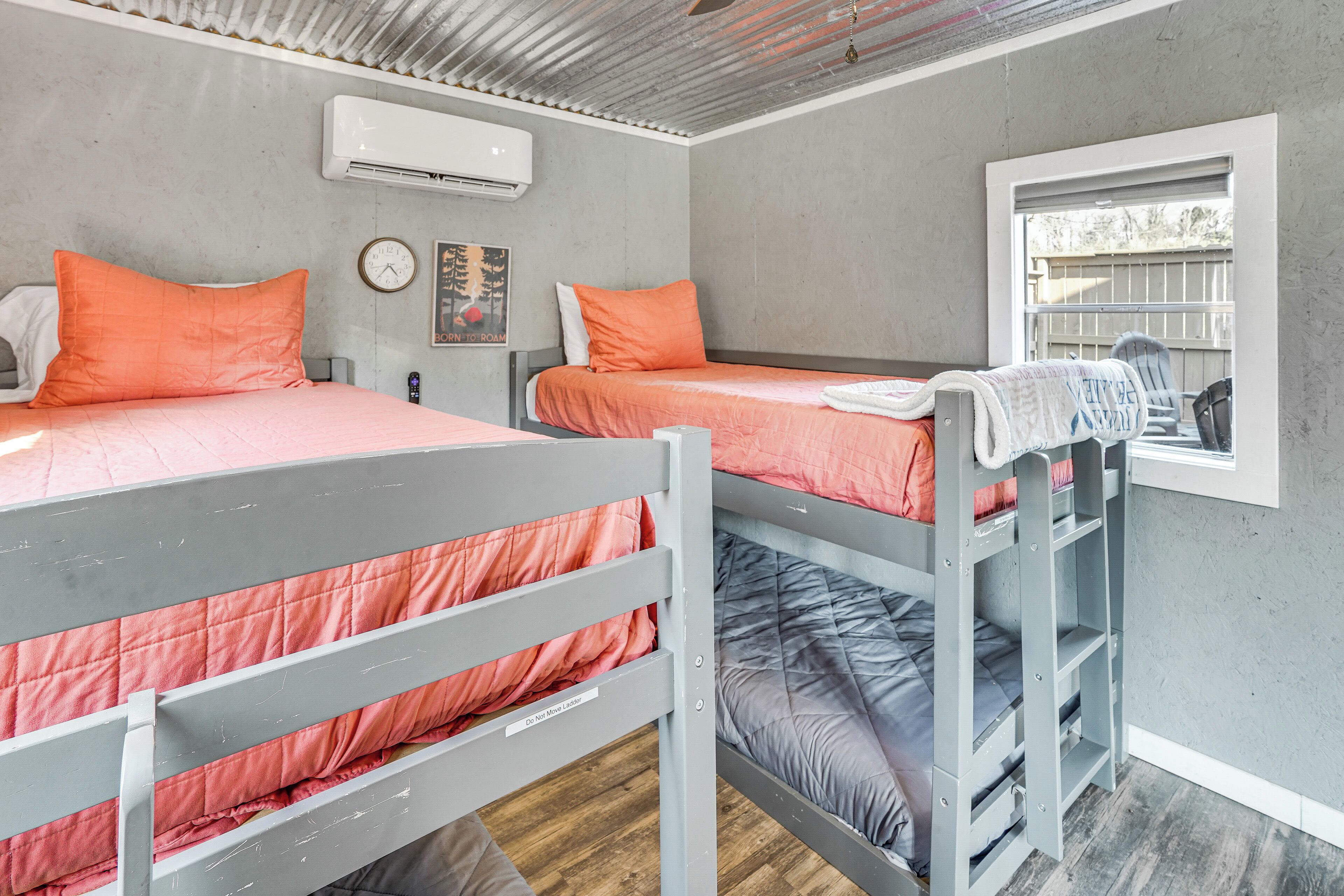 Een kamer met stapelbedden, een airconditioning, een klok en een raam met uitzicht.