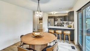 A modern kitchen with dark cabinets, a central island, and a dining area with a round wooden table and chairs. - 3 Mi to Beach From 'the Harbor Collective' (New Buffalo)