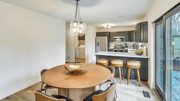Una cocina moderna con armarios oscuros, una isla central y un comedor con una mesa redonda de madera y sillas.