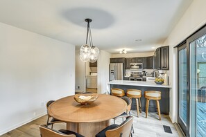 A modern kitchen with dark cabinets, a central island, and a dining area with a round table and chairs. - 3 Mi to Beach From 'the Harbor Collective' (New Buffalo)