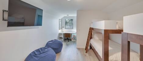 Una habitación con literas, un escritorio, una silla y un ventilador de techo.
