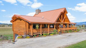 A log cabin with a porch, a chimney, and a gravel driveway. - Group Retreat in the Bitterroot Valley w/ Hot Tub (Victor)