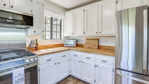 Una cocina con armarios blancos, un refrigerador de acero inoxidable, un horno empotrado y una ventana con vistas.