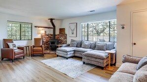 Una sala de estar con chimenea, sillones de cuero, un sofá modular y ventanas grandes.