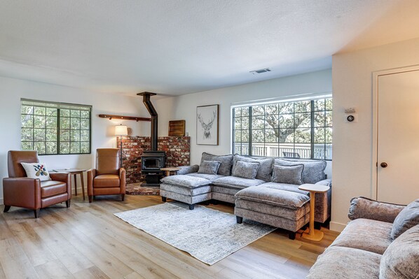 A living room with a fireplace, leather chairs, a sectional sofa, and large windows.
