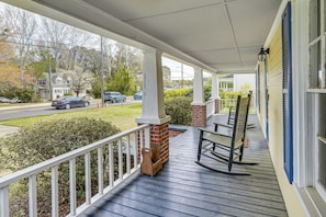 A porch with a wooden railing, a rocking chair, and a brick column. - Half-mi to Dtwn Wendell! 60s Farmhouse w/ Fire Pit (Wendell)