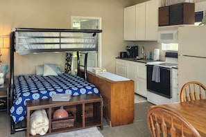 A bunk bed with a desk and chair, a microwave, stove, and cabinets in a compact kitchen area. - Ozark Mountain Launchpad! Cabin w/ Fishing On-site (Richland)