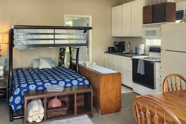 A bunk bed with a desk and chair, a microwave, stove, and cabinets in a compact kitchen area. - Ozark Mountain Launchpad! Cabin w/ Fishing On-site (Richland)