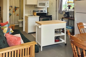 A compact kitchen with a microwave, stove, and sink. There is a small wooden table and a chair. - 'stargazer's Delight' in the Ozarks: Country Cabin (Richland)